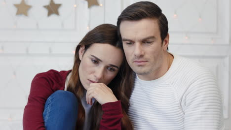 Portrait-of-thinking-couple-sitting-in-living-room-together