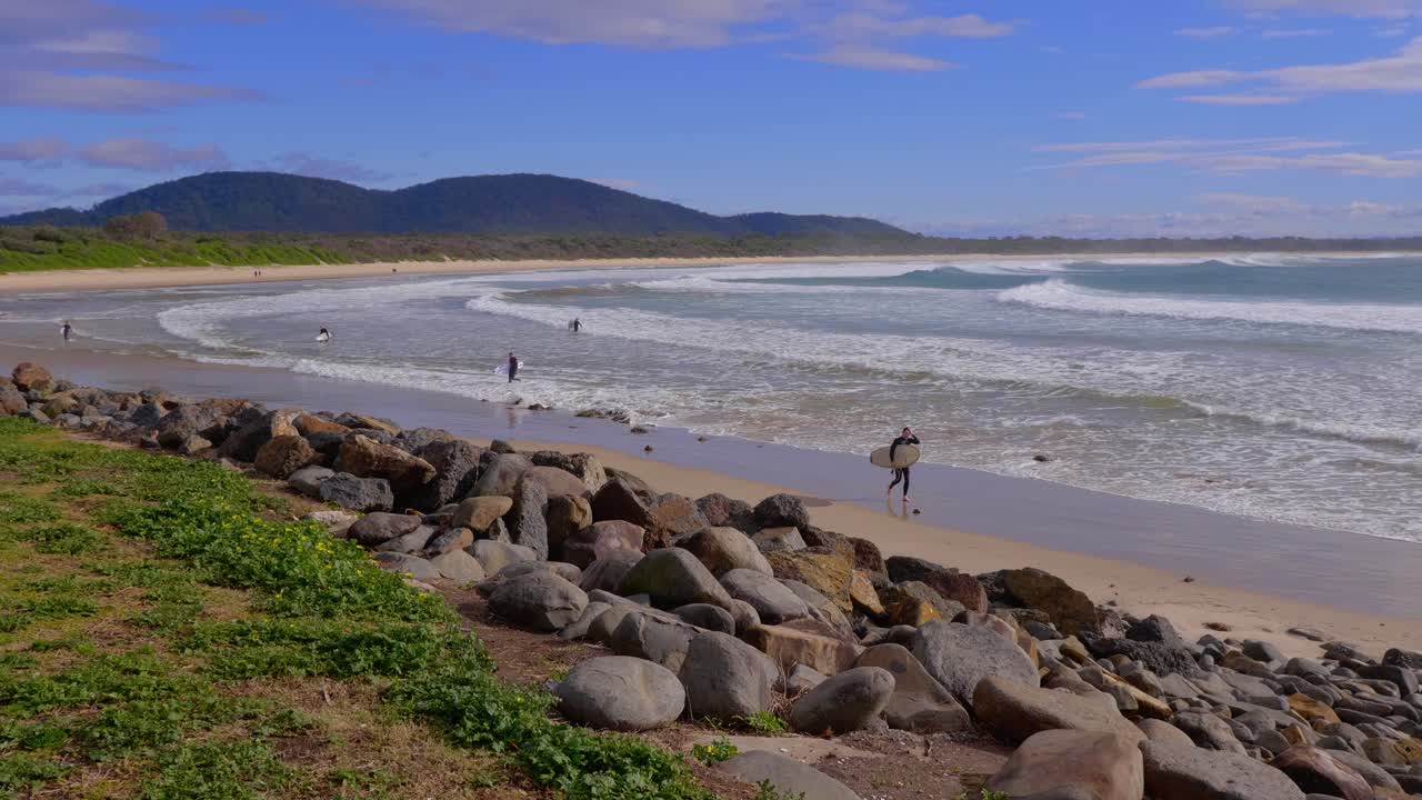 surfistas que se alejan del océano después de surfear - día de verano en la playa en crescent head en nueva gales del sur - plano general
