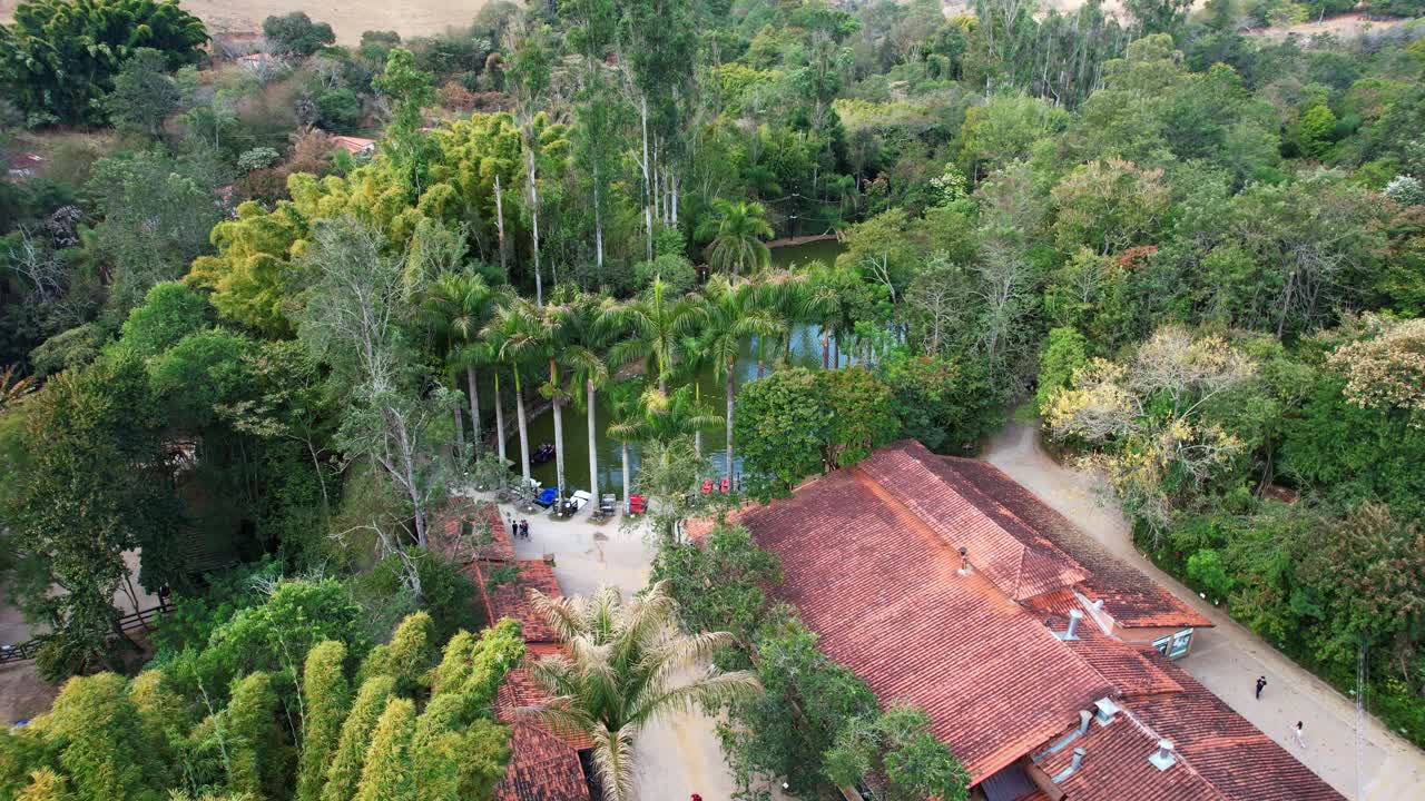 Aerial drone shot showing structures and houses with palm trees surrounding a beautiful lake with colorful boats and people having fun
