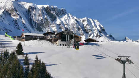 Colorful-cable-cars-entering-the-mountain-station-Tschentenegg-in-Adelboden-Switzerland-on-a-sunny-winter-day