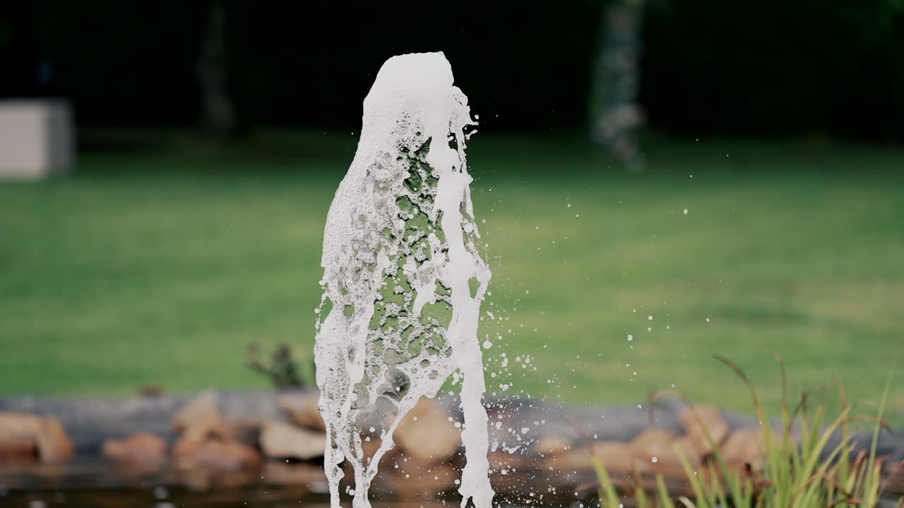 Dynamic Water Fountain Jet Against Green Lawn