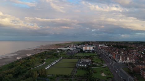 aerial view of a coastal town at dusk, featuring beach, pier, and urban landscape