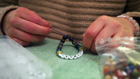 woman hand double tying a handmade bracelet with letters, close up