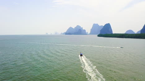 Long-tail-boats-cruising-in-tropical-sea-near-islands-of-Ao-Phang-Nga