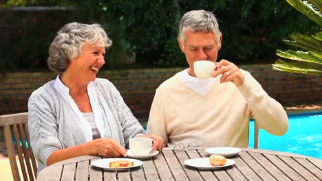 una pareja madura riendo con un café.