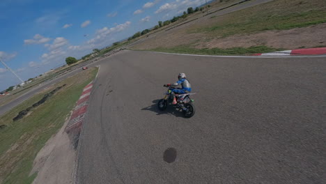 energetic fpv drone pov following motorcycle riders turning on racing circuit, aerial view