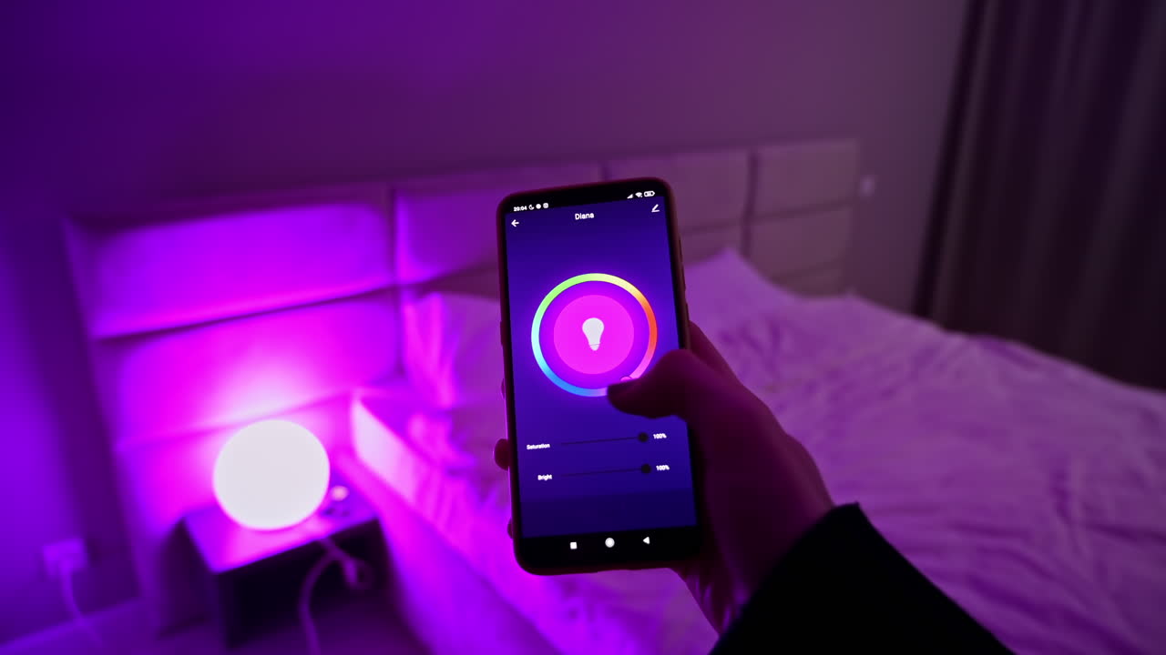 Woman hands holding smartphone, changing color light in hue app in the bedroom. Smart home