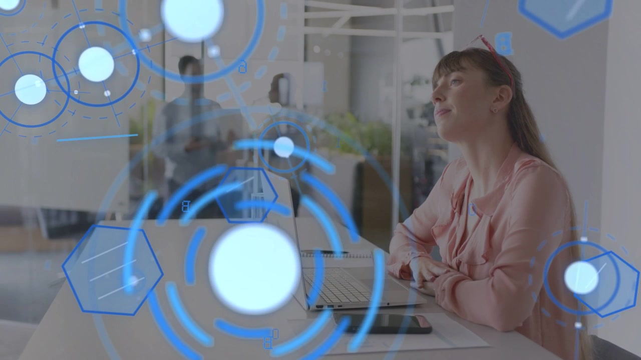 Kvinde bruger bærbar computer og telefon, HUD vises over skærmen, gennemgår tekniske data, mænd gennem glas.