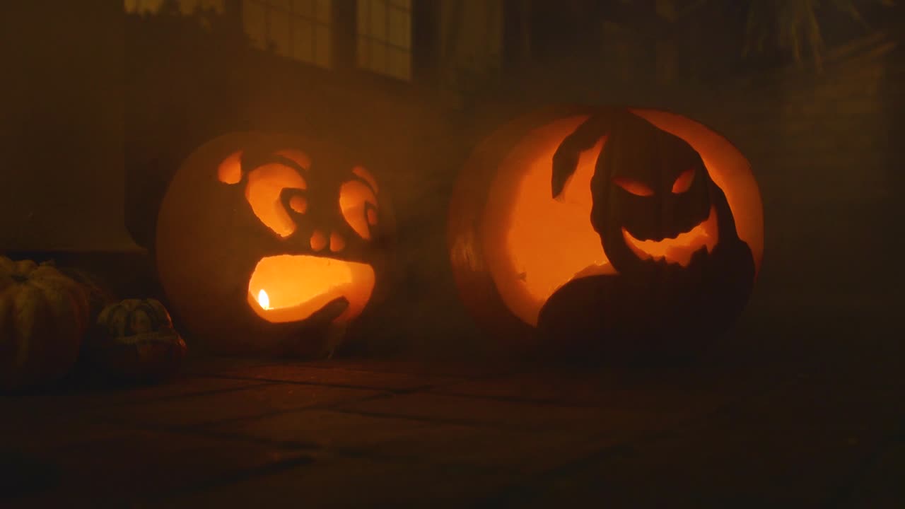 2 carved lit pumpkin outside the front of a house Halloween with smoke slow motion