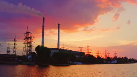 industry against beautiful evening sky. chemical factory and high-voltage electric lines on the riverbank at sunset. pollution of the environment.