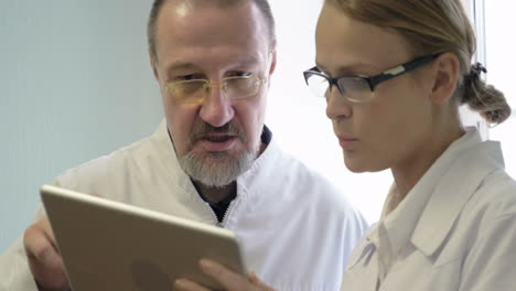 médicos masculinos y femeninos discutiendo algún problema usando una tableta
