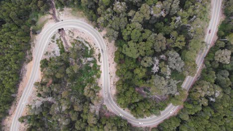 Straight-down-aerial-tracks-car-traffic-on-rural-highway-tight-S-curve