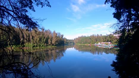 Unberührter,-Ruhiger-Wassersee-Mit-Reflexion-Des-Beruhigenden-Blauen-Himmels-Und-Umgeben-Von-Grünen-Wäldern.-Video-Aufgenommen-Am-Ooty-Lake-Tamilnadu,-Indien