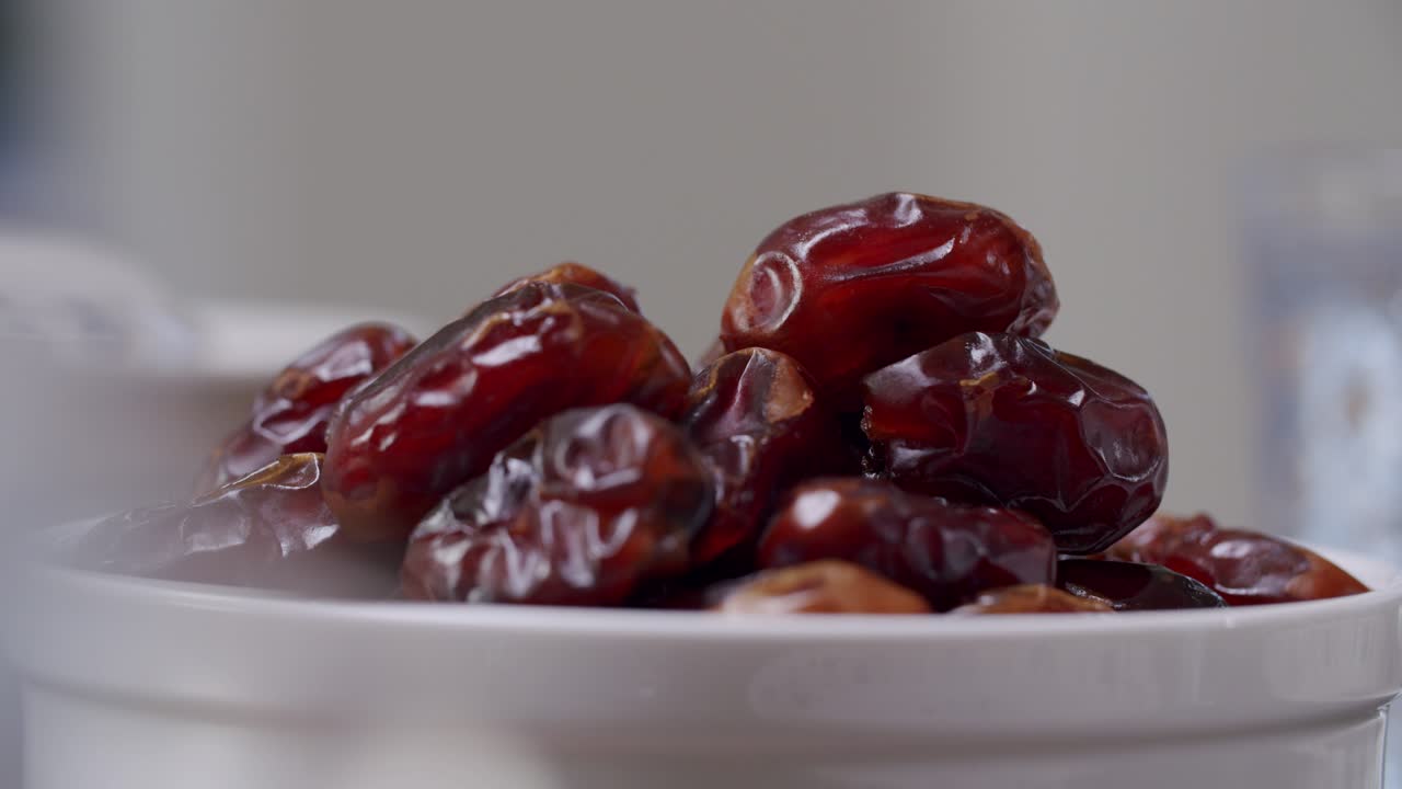 Hand Picks Up Sweet Date Fruit From Heap In A White Bowl