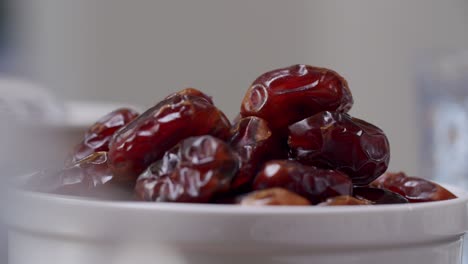 hand picks up sweet date fruit from heap in a white bowl