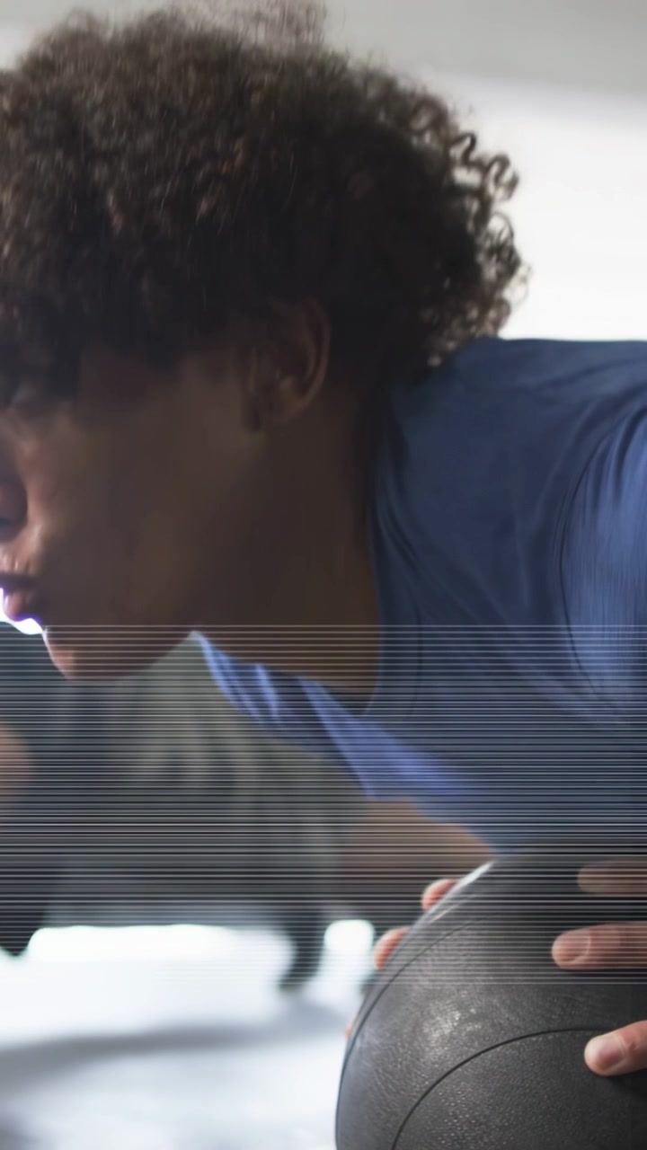 Vertical video: Man in blue tee gripping ball 15 and doing plank pushes for fitness