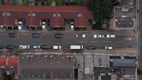 Aerial-birds-eye-overhead-top-down-descending-view-of-street-in-residential-district-with-cars-parked-along-road.-London,-UK