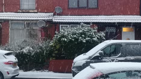 Snow-covered-vehicles-parked-outside-English-red-brick-terrace-houses-on-freezing-winter-morning