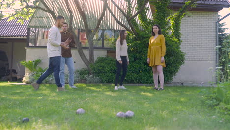 front view of caucasian young woman throwing a petanque ball in the park on a sunny day