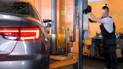 mechanic working on a car lift in an auto repair garage