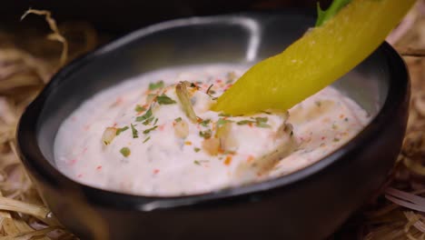 Static-Shot-of-Yellow-Bell-Pepper-Dipping-into-Creamy-Herb-Dip-in-Black-Bowl