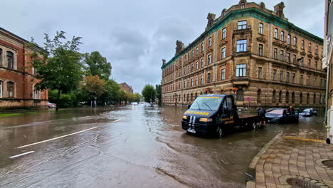 tow truck assists submerged car on a heavily flooded city street after heavy rain