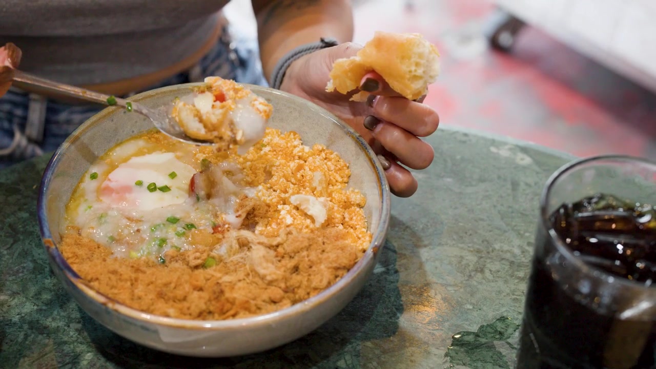 Orang Makan Bubur Nasi Asia dengan Topping di Restoran
