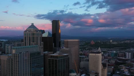 Schwenkantenne-Der-Skyline-Der-Innenstadt-Von-Seattle-Mit-Einem-Wolkigen-Und-Kühlen-Sonnenuntergang-Im-Hintergrund