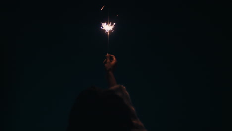young-woman-holding-sparkler-on-rooftop-at-night-celebrating-new-years-eve-looking-at-sparks-enjoying-festive-celebration