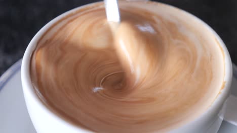 closeup of a cup of coffee being stirred with a spoon