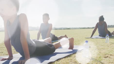 animation of light spots over happy diverse schoolboys stretching in outdoor yoga class