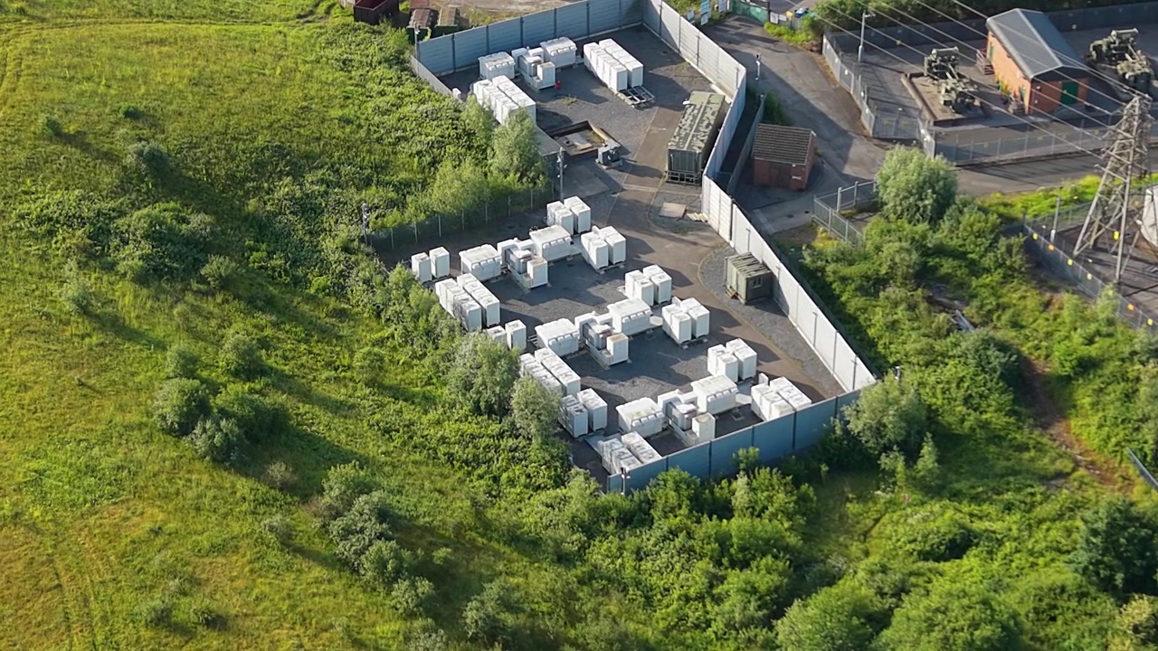 Modulært BESS (Battery Energy Storage System) batterienergilagringssystem, der lagrer vedvarende energi. Netstyring, AI-energioptimering og bæredygtig infrastruktur. Storbritannien. 4K.