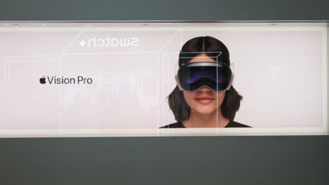 people walk past a poster outside the american multinational technology company's store showcasing the apple vision pro, apple's new mixed-reality headset, in hong kong.