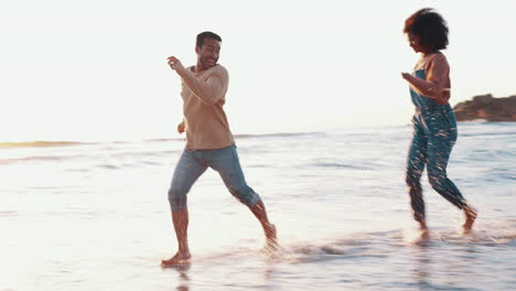 pareja, corriendo y salpicando agua en la playa