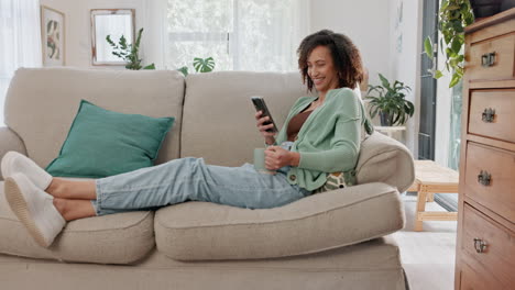 mujer sonriendo en un sofá mirando su teléfono