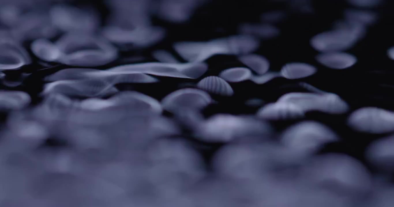 Extreme close up macro of black fluid having large ripples and settling