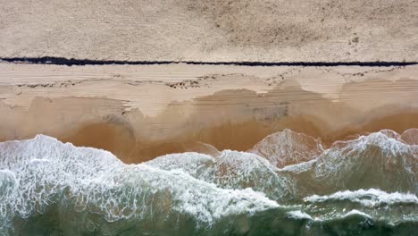 Bird's-eye-aerial-shot-of-the-tropical-Rio-Grande-do-Norte,-Brazil-coastline-with-golden-sand,-turquoise-clear-water-and-turbulent-waves-crashing-on-shore-in-between-Baia-Formosa-and-Barra-de-Cunha?