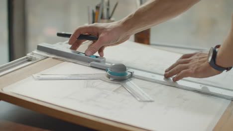 engineer draws buildings on the table using a pencil and ruler. an architect creates a building design on paper using a marker and ruler.