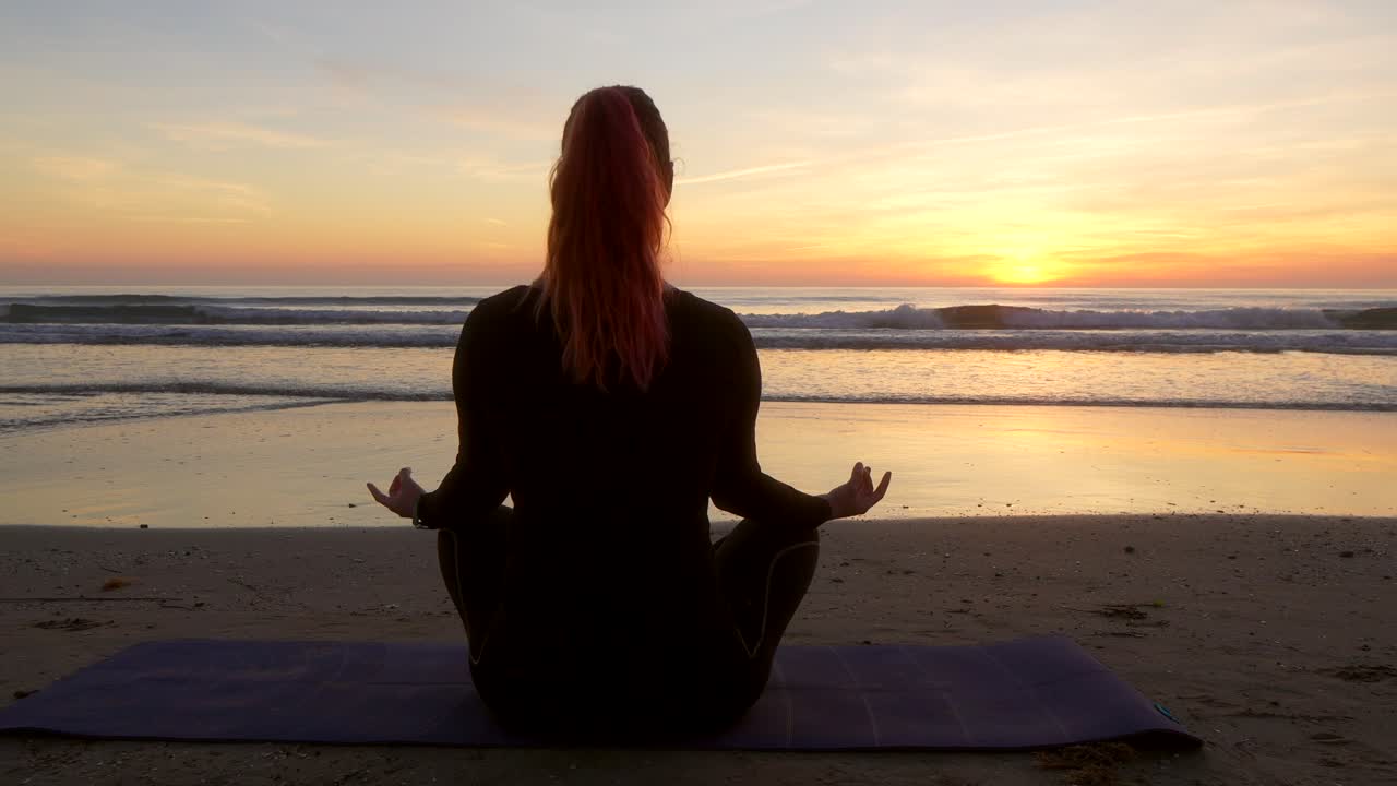 mujer meditando al amanecer en la playa