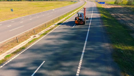 Traktor-Fährt-Auf-Der-Autobahn.-Drohnenansicht-Traktor,-Der-Auf-Der-Landstraße-Fährt