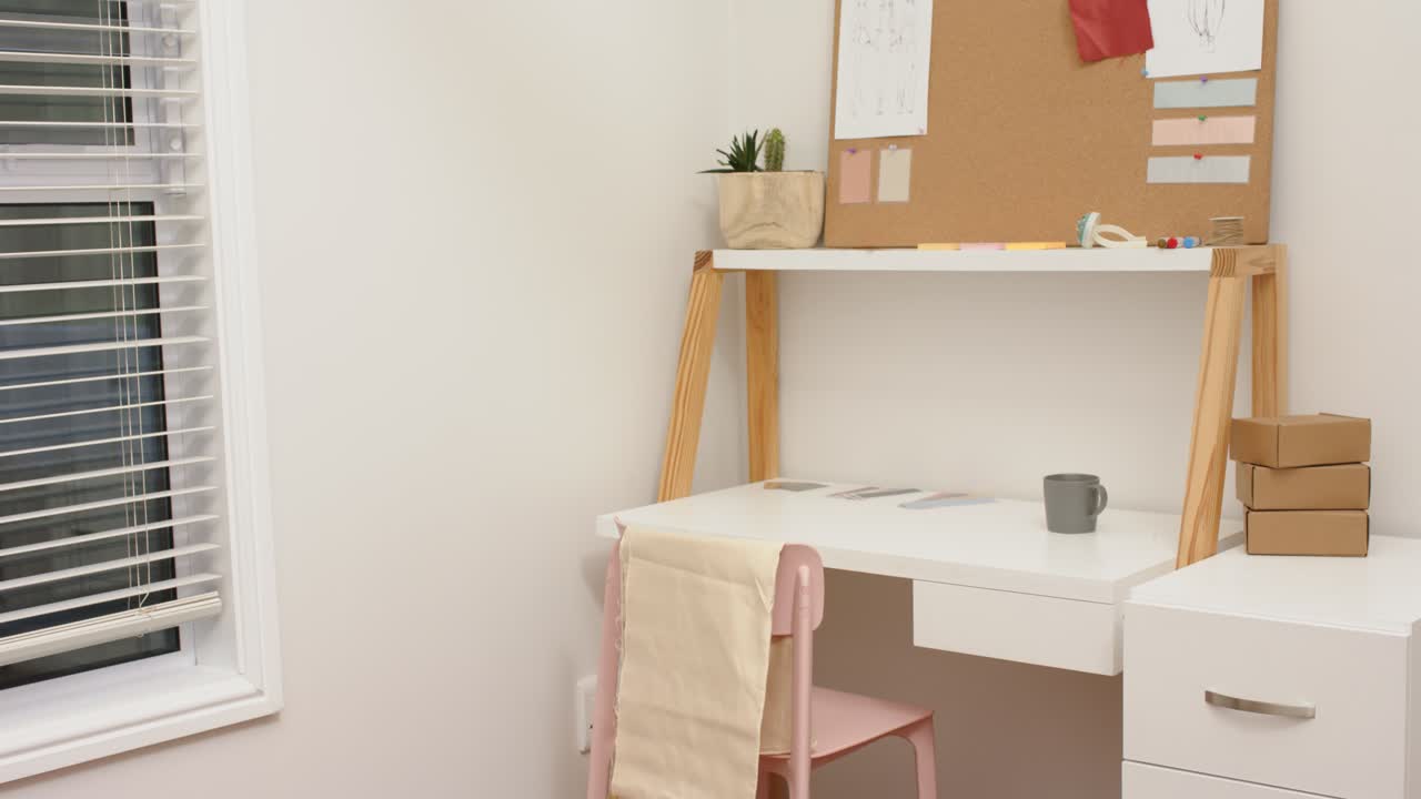 Camera starting on dress rack, panning right showing white desk, pink chair, mug and bulletin board