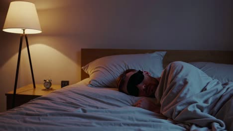 man sleeping in bed with sleep mask