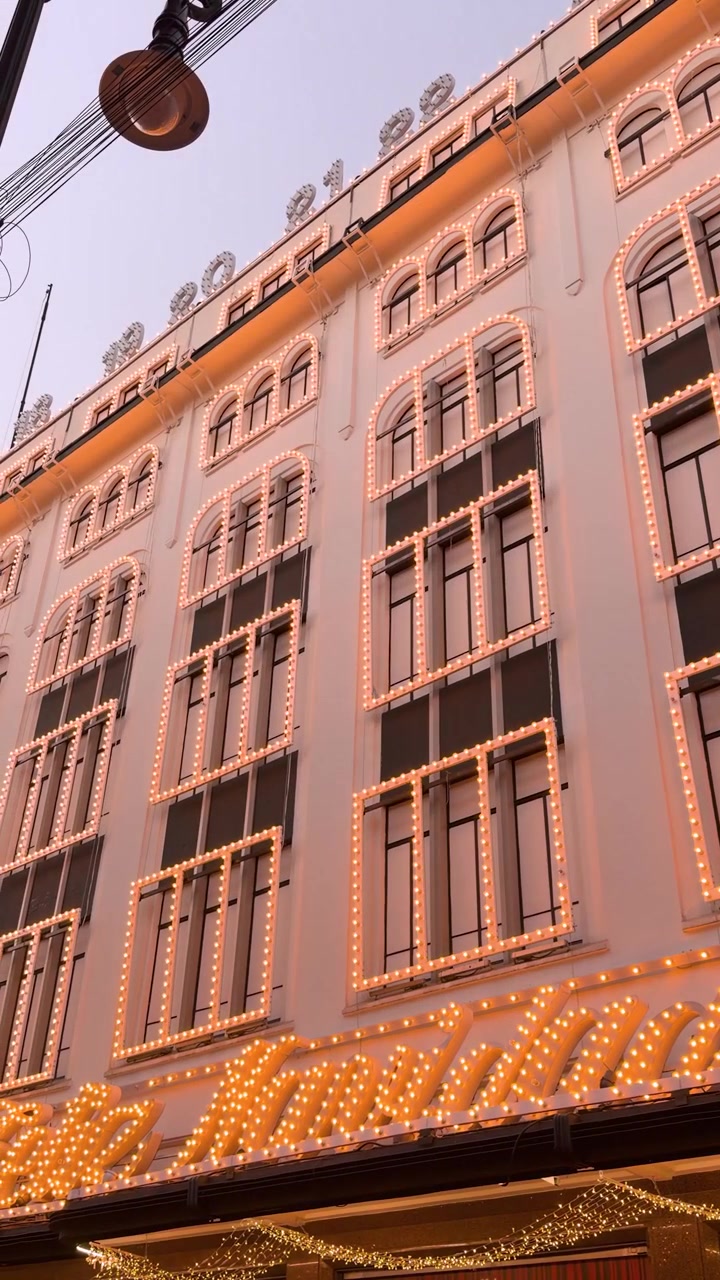 Fachada de edifício decorada com luzes de Natal festivas ao anoitecer em rua da cidade