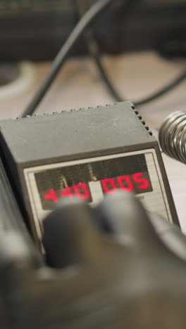 una vista de cerca de la mano de un técnico con un guante negro ajustando un dispositivo de control de temperatura digital