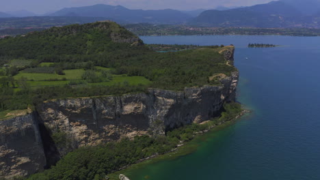 aerial shot closing in to the cliffs of manerba at lago di garda on a bright sunny day