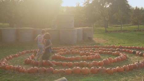 village children play in the fall. pumpkins are stacked in spiral on the ground.