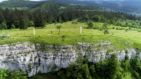 Aerial-drone-shot-of-Enduro-Biker-starting-race-from-peak-of-Jura-Mountains-downhill