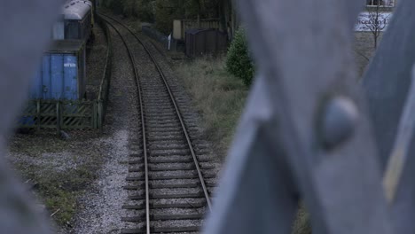 Train-track-with-parked-carriages-view-through-bridge-wide-tilting-shot