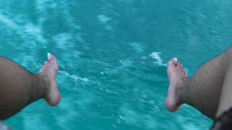 feet splashing on the turquoise water while riding on a boat