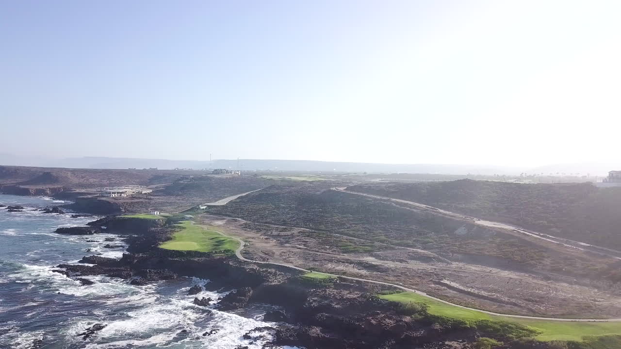 Drone flyr fra høyre til venstre med store, vide utsikter over en strandnær golfbane og Baja-ørkenlandskapet.